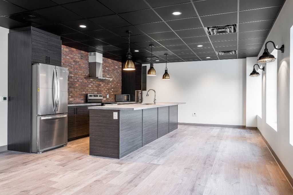 Party room kitchen with brick accent wall and stainless appliances