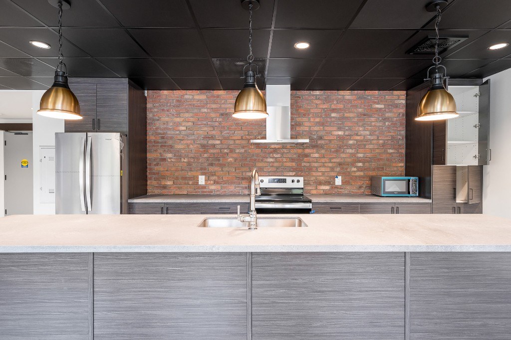 Party room kitchen island with pendant lighting and brick backsplash